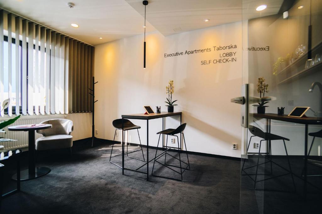 vestíbulo con 2 mesas y taburetes en una habitación en Executive Apartments Taborska, en Mladá Boleslav