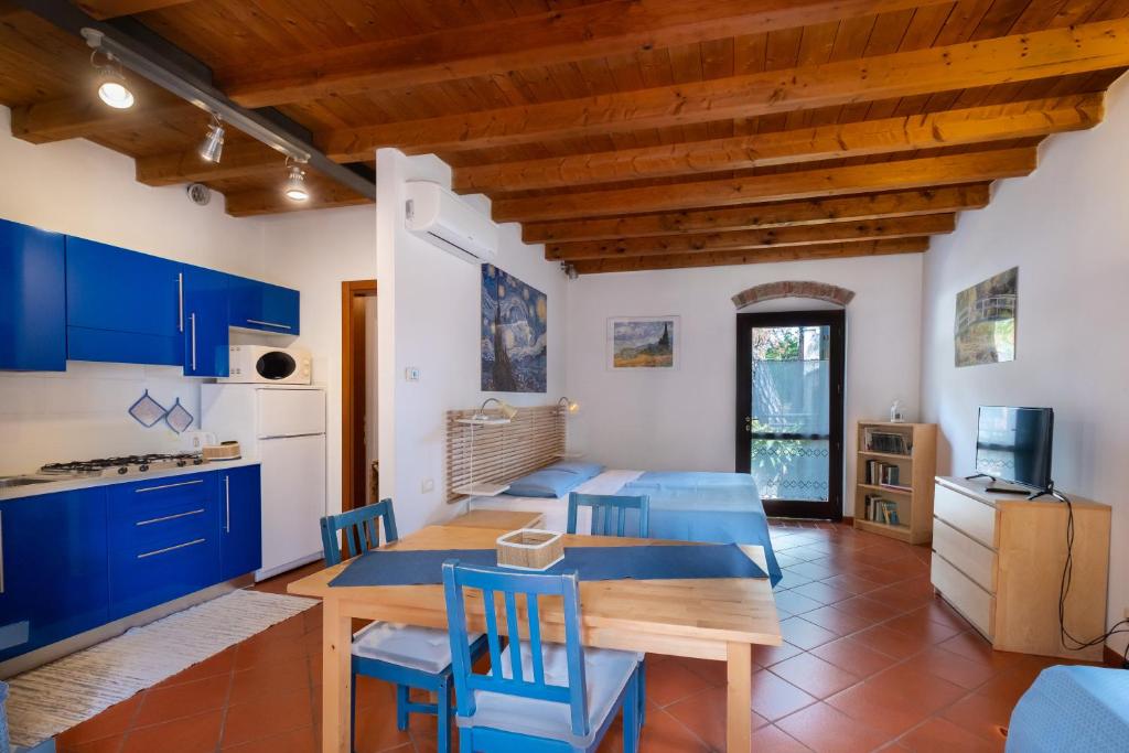 ヴェローナにあるCorte Roveggia - Monolocale Van Goghのキッチン、ダイニングルーム(青いキャビネット、木製テーブル付)