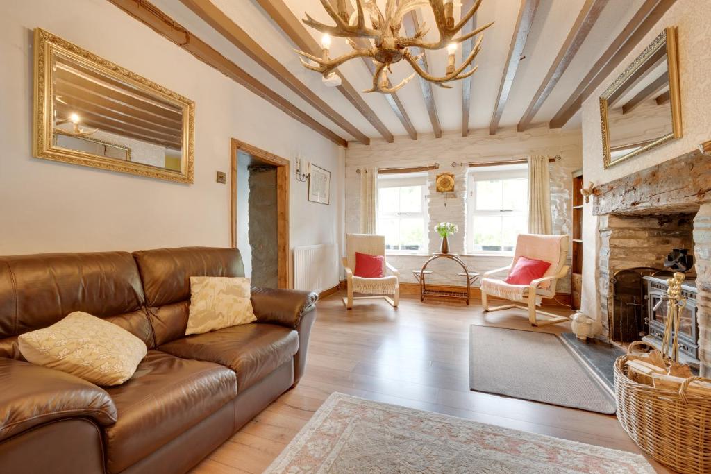 a living room with a leather couch and a fireplace at Gwel y Bryn in Corris