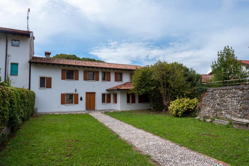 a white house with a stone wall and a yard at B&B LA SCALA in Paludea
