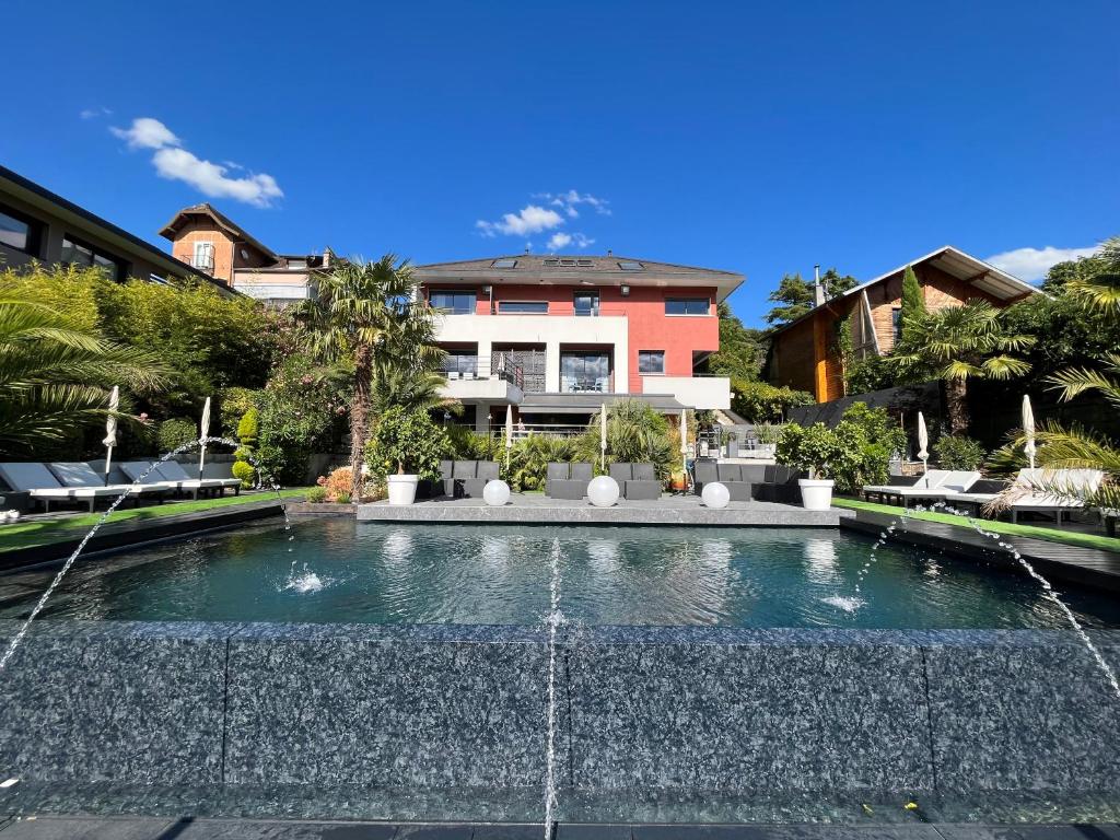 a house with a fountain in front of a house at Les Suites du Lac in Aix-les-Bains