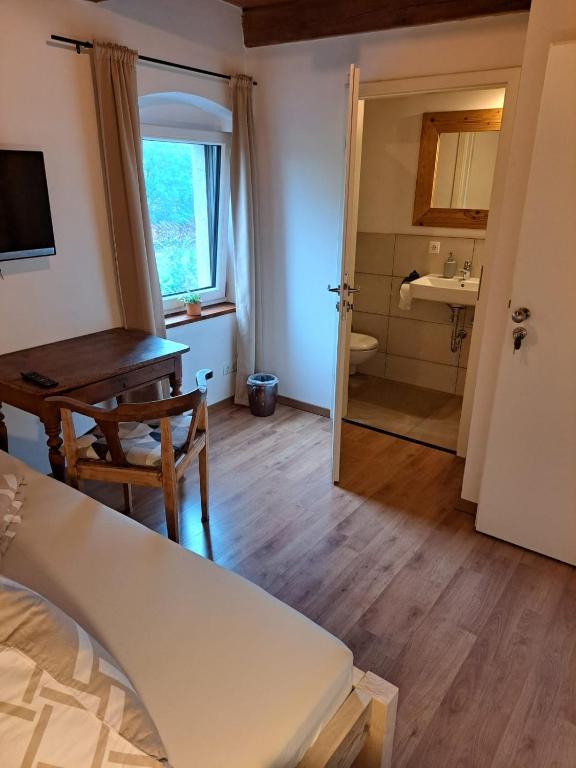 a bedroom with a desk and a table and a bathroom at Pension Müllers Mühle in Großenhain