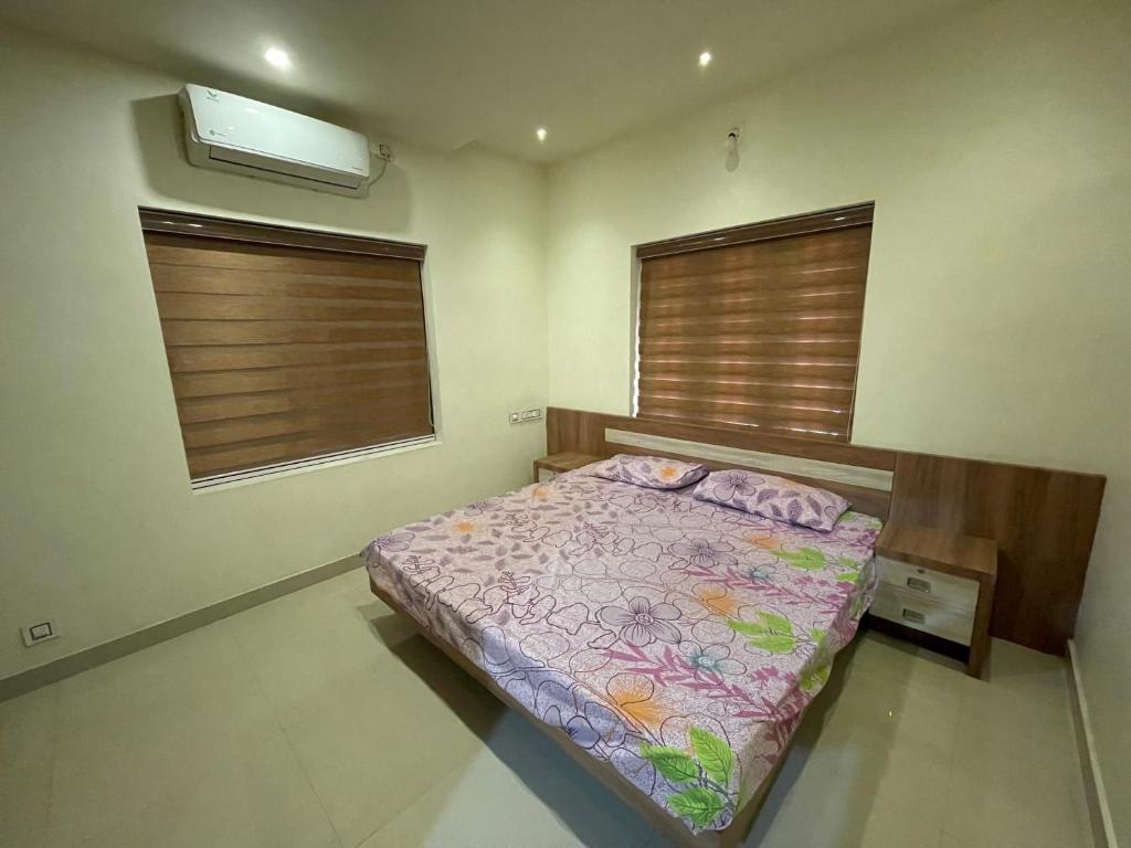 a bedroom with a bed and two windows at Kottakkal Villa2 in Kottakkal