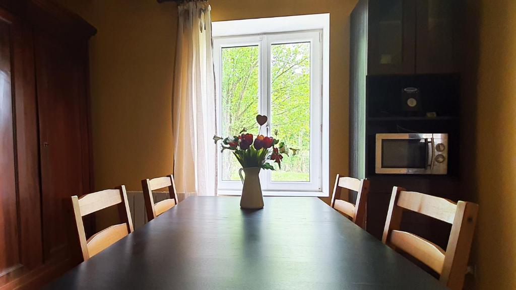 una mesa de comedor con un jarrón de flores en una ventana en Le bois de l'étang - Gîte 3 étoiles - 6 pers, 