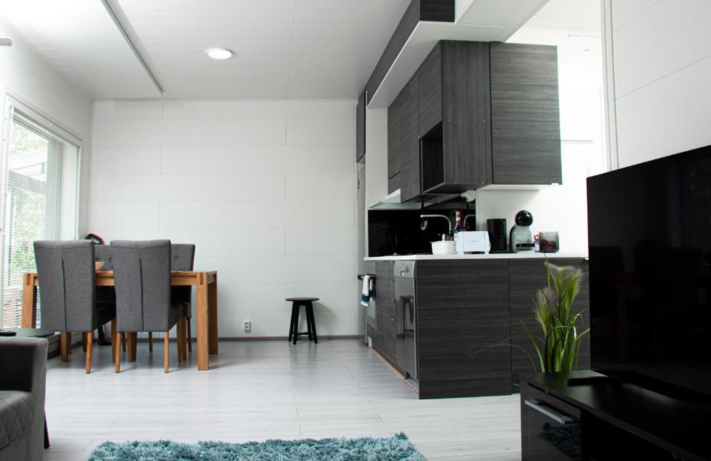 ein Wohnzimmer mit einem Tisch und einer Küche in der Unterkunft Talo saunalla ja sähköauton oma Type2 latauspiste in Vantaa
