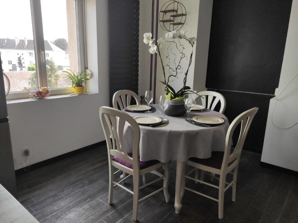 a dining room table with chairs and a white table cloth at Appartement cosy centre-ville wifi parking in Charleville-Mézières