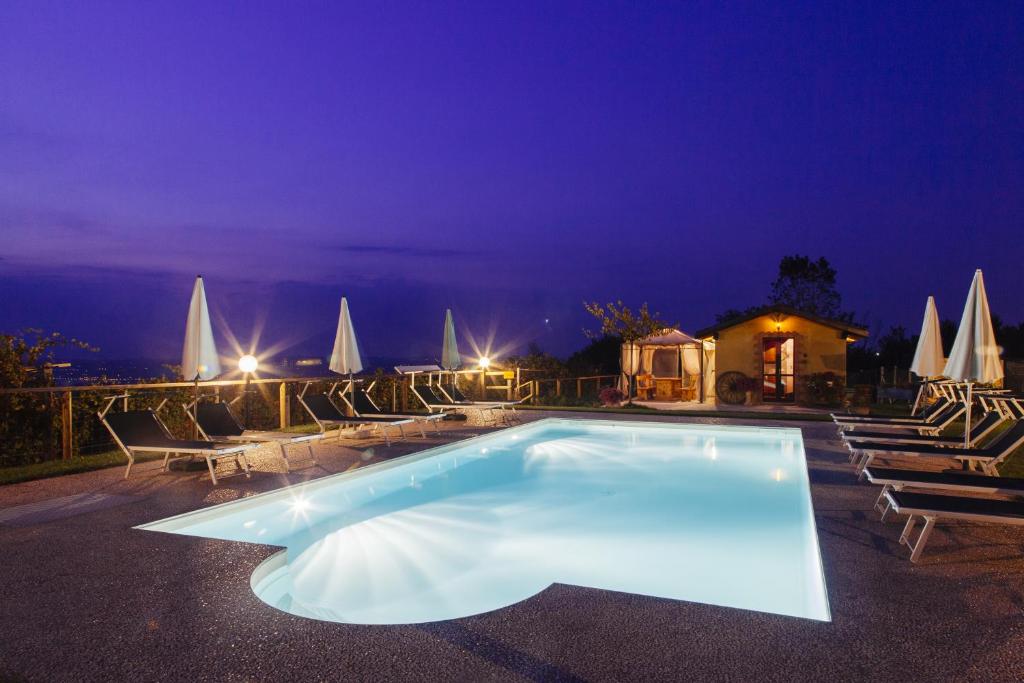 a swimming pool at night with chairs and umbrellas at Il Grappolo Vacanze in La Morra