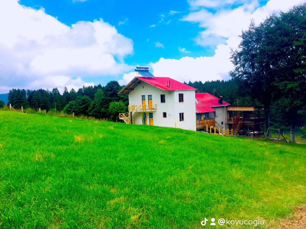 een wit huis met een rood dak op een groene heuvel bij ACISU CAFE KONAKLAMA in Trabzon