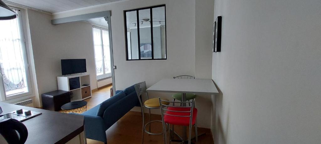 a living room with a blue couch and a table at Appartement coquet sur les hauteurs de Montmartre in Paris