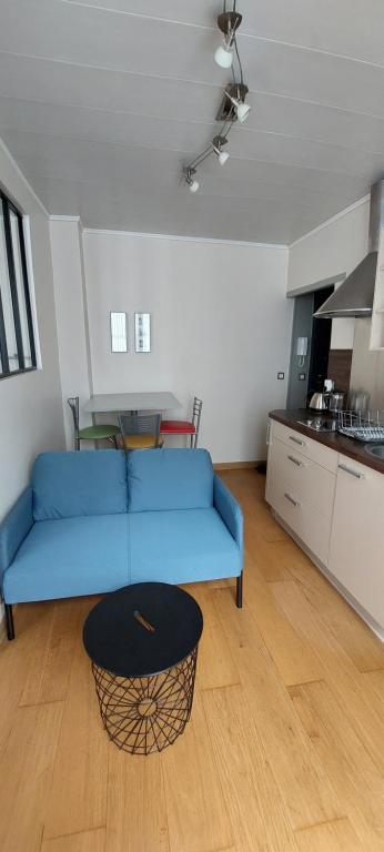 a living room with a blue couch and a kitchen at Appartement coquet sur les hauteurs de Montmartre in Paris