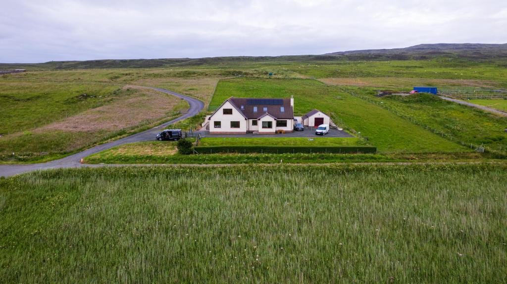 a house in the middle of a grassy field at Trumpan Cottage Bed & Breakfast in Trumpan