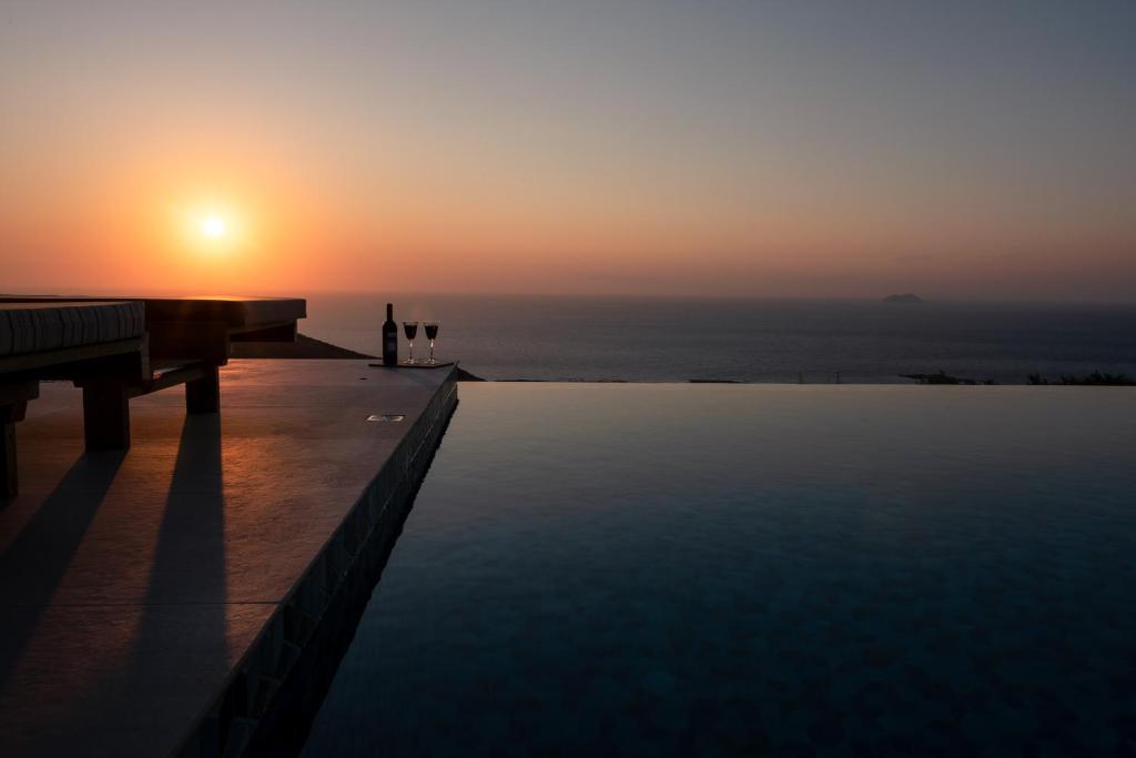 a sunset over a swimming pool with a piano at Alma Natura Villas Falasarna- Aphroditi Villa in Falasarna