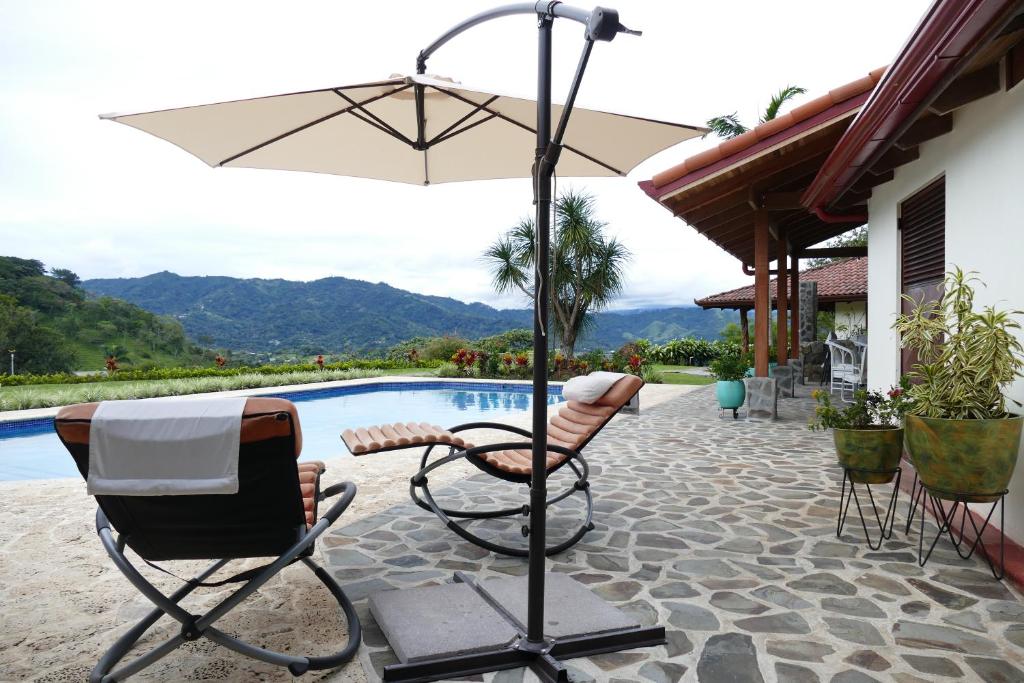 eine Terrasse mit Stühlen und einem Sonnenschirm neben einem Pool in der Unterkunft Bungalows Sanlaz in Jesus