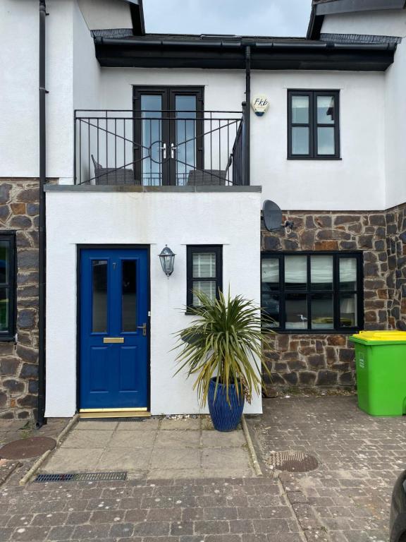 een huis met een blauwe deur en een plant bij Waters Reach in Abersoch