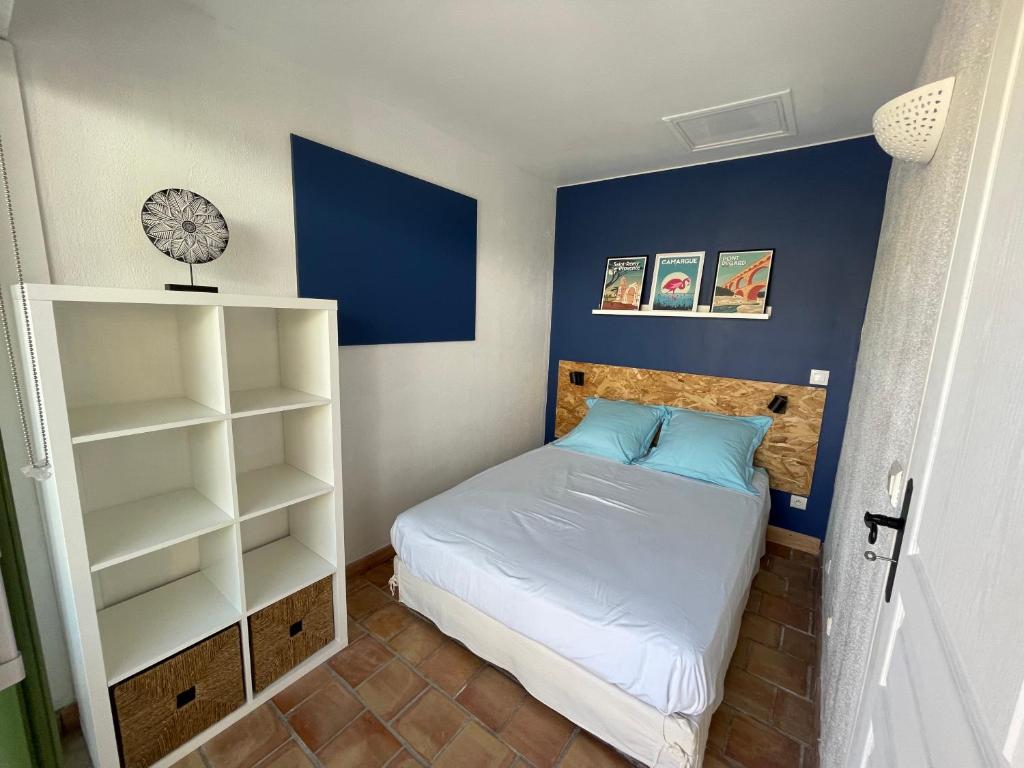 ein kleines Schlafzimmer mit einem Bett und einer blauen Wand in der Unterkunft Le Mazet de Lola in Saint-Rémy-de-Provence