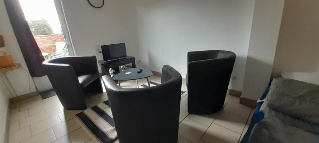 a living room with chairs and a table and a couch at Maison des Flandres in Oxelaere