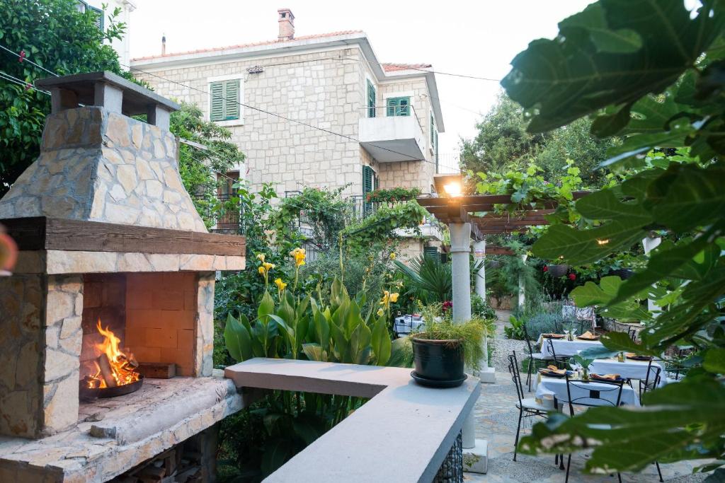 eine Terrasse mit einem Kamin, einem Tisch und Stühlen in der Unterkunft B&B Villa Dubrovnik Garden in Dubrovnik