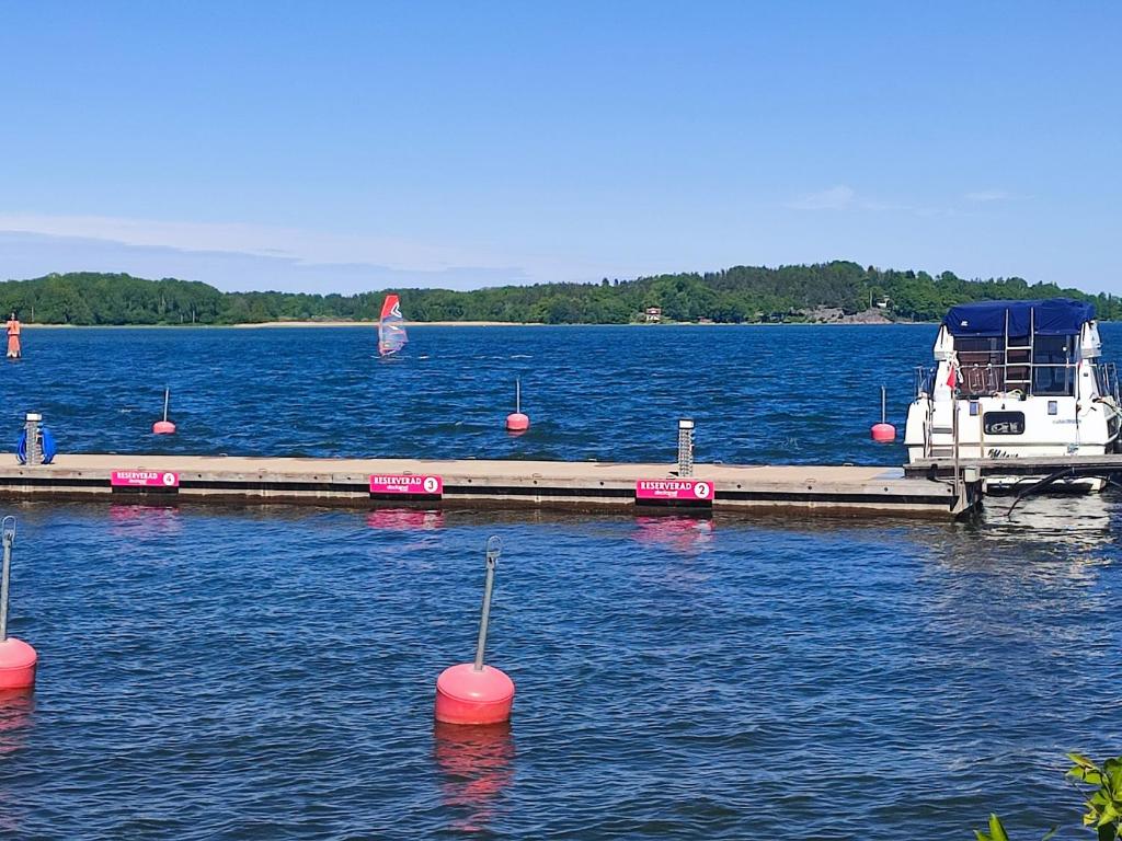 un muelle con boyas rojas en el agua con un barco en Den Unika Sekelskiftsvåningen., en Norrtälje