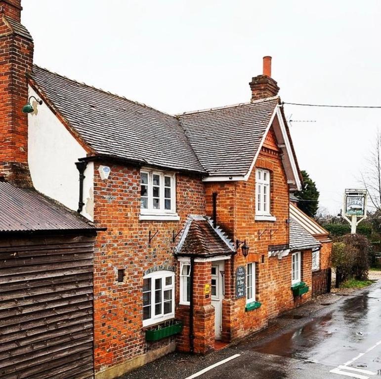 a brick house with white windows on a street at The Six Bells in Newbury