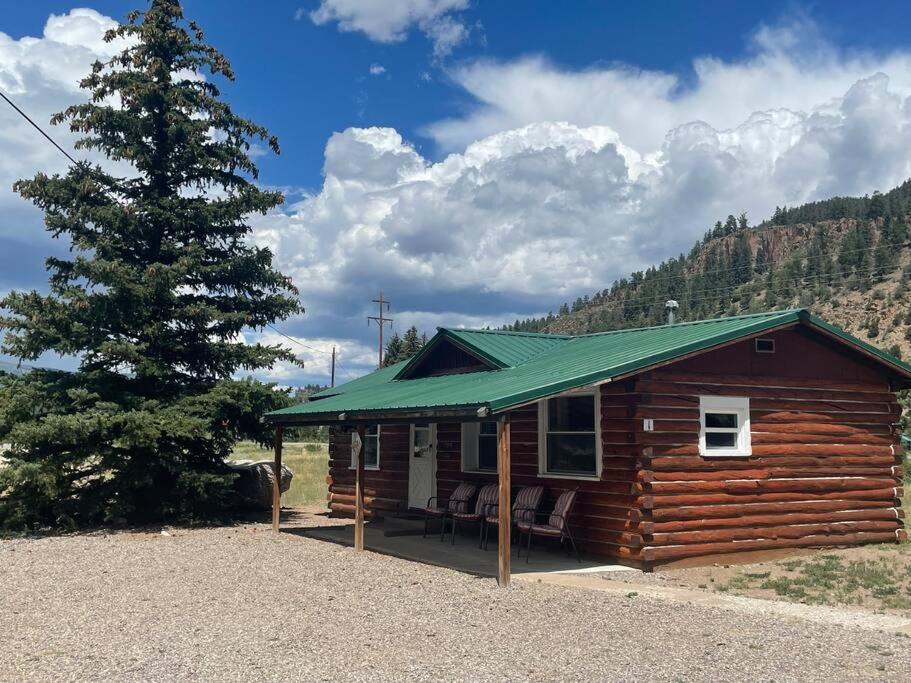 Cabaña de madera con techo verde junto a un árbol en Cozy cabin #1 at Aspen Ridge Cabins, en South Fork