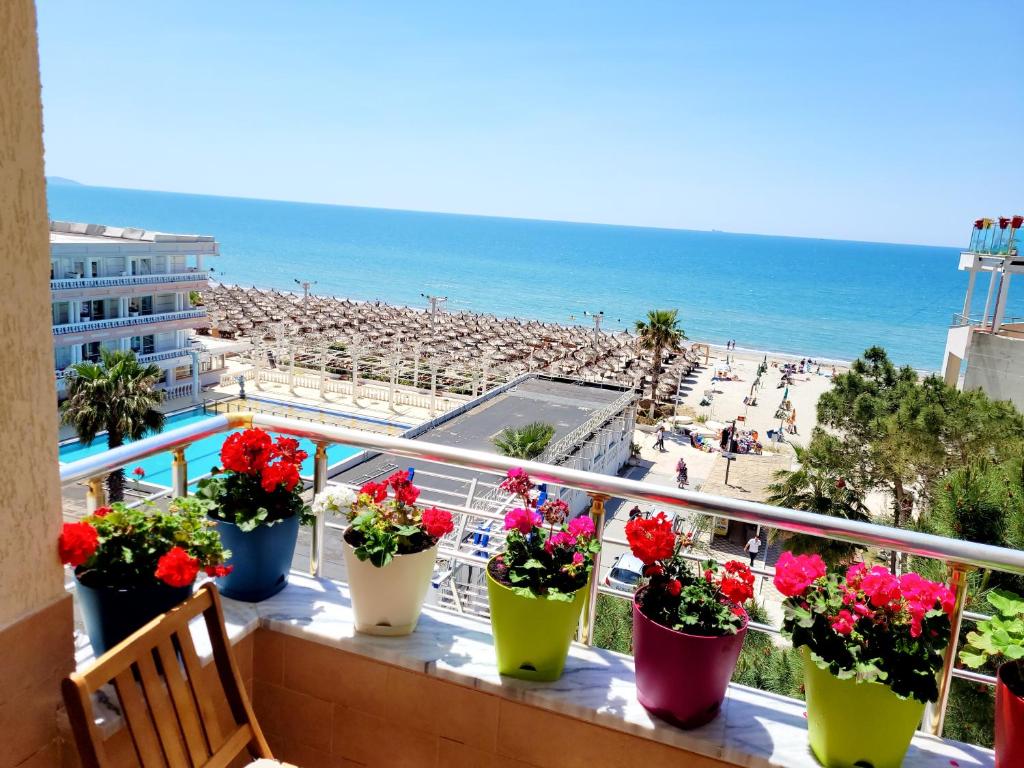 a balcony with flowers inront of a beach at Sea View New Apartment in Durrës