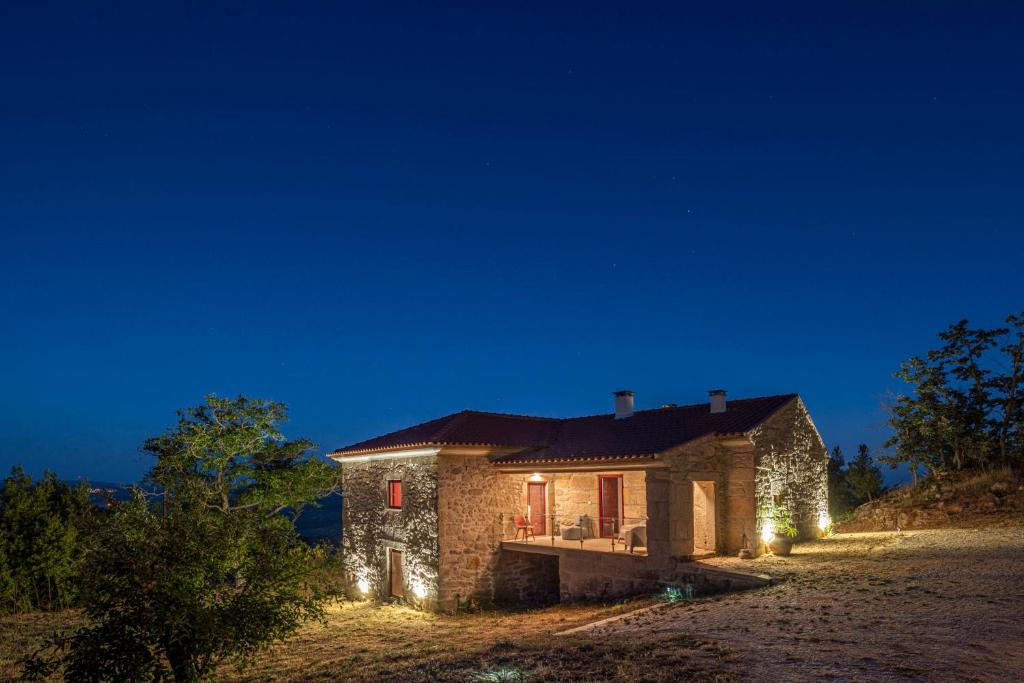 una casa de piedra con luces encendidas por la noche en Casa da Moiroa, en Sendim