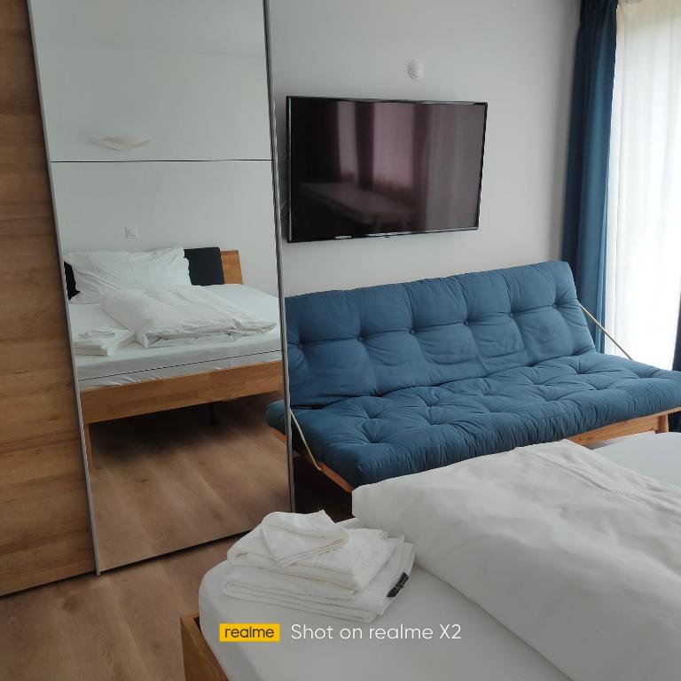 - un canapé bleu dans une chambre avec un miroir dans l'établissement Herberge Balmweid 1, à Meiringen