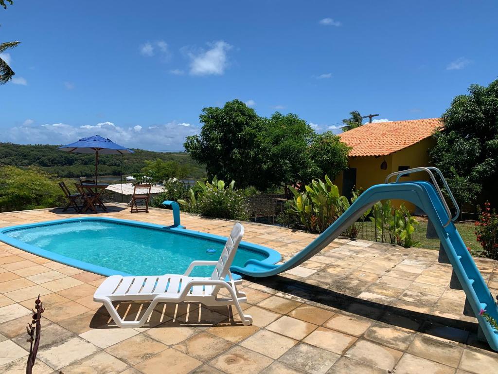 a pool with a slide and a chair and a slidesktop at Sítio Vila das Flores in Tibau do Sul