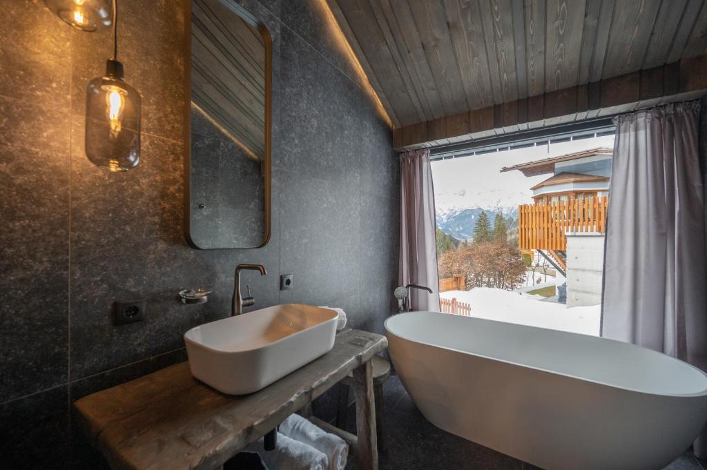 baño con bañera, lavabo y ventana en Paznauner Villen - Villa II en Kappl