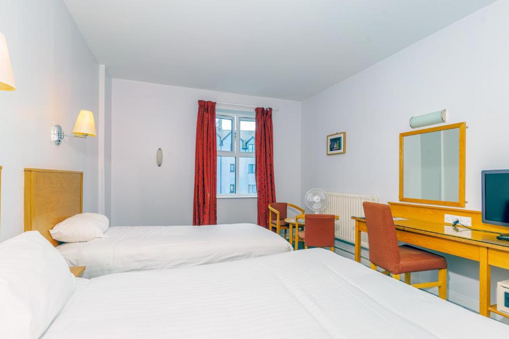 a room with three beds and a desk with a computer at Portrush Atlantic Hotel in Portrush