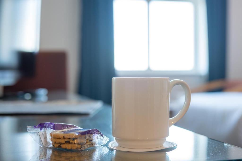 a white coffee cup sitting on a table next to a cookie at Portrush Atlantic Hotel in Portrush