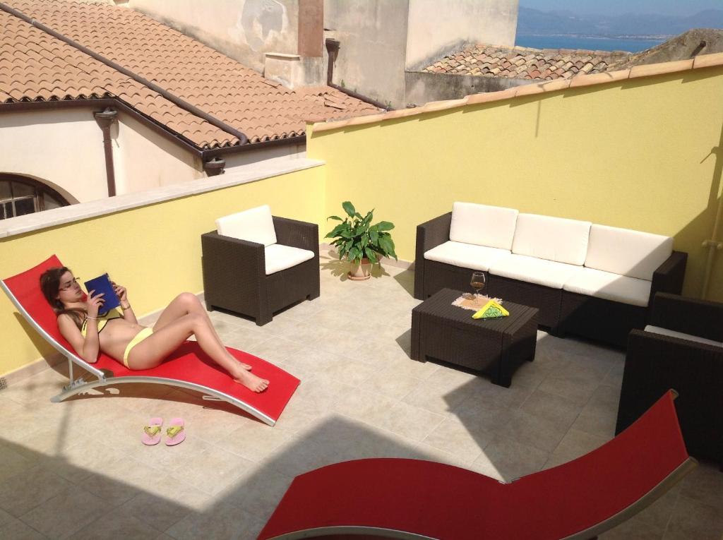 une femme assise sur une chaise en lisant un livre dans l'établissement Casa Vacanze Madrice, à Castellammare del Golfo
