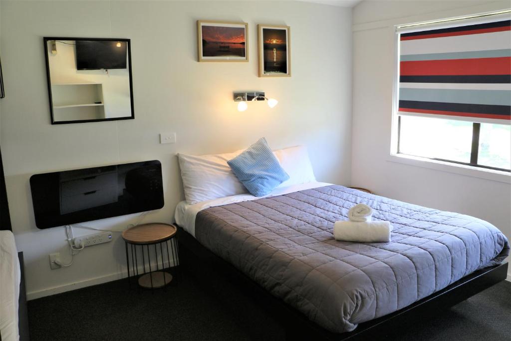 ein kleines Schlafzimmer mit einem Bett und einem TV in der Unterkunft Kaiteriteri Reserve Cabins in Kaiteriteri