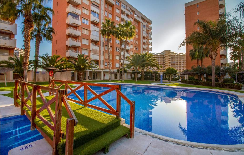 a large swimming pool with palm trees and buildings at Beautiful Apartment In Alicante alacant With Outdoor Swimming Pool in Benimagrell