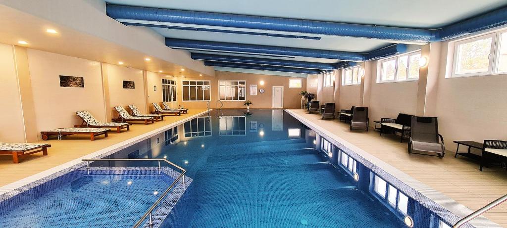 a large swimming pool in a building with chairs at ApartHotel Olympus Plaza in Kranevo