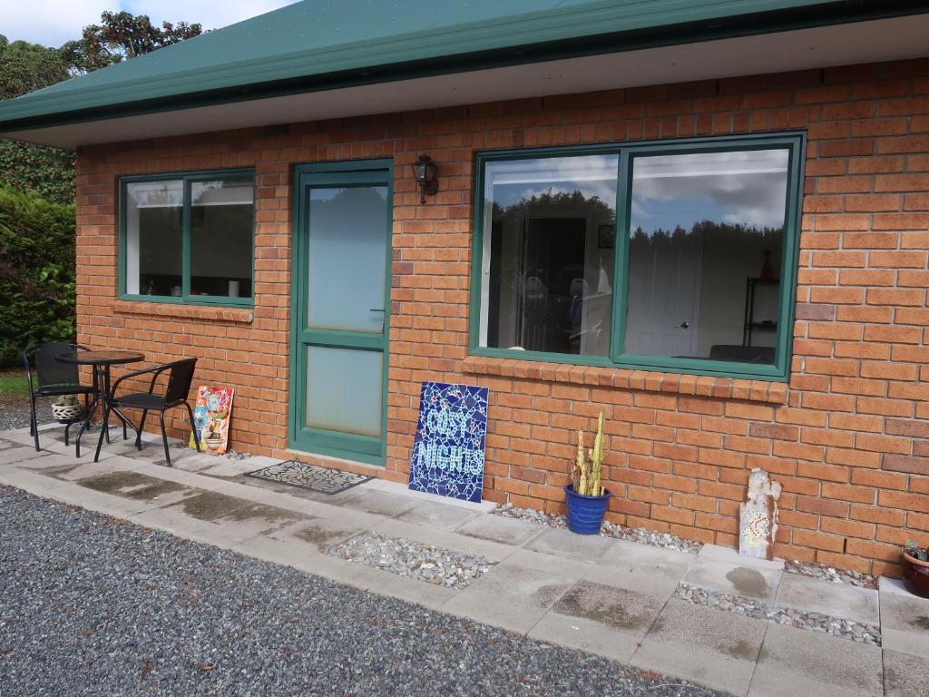 a brick house with a table and a window at Cosy Nights - modern, self-contained with parking in Kerikeri
