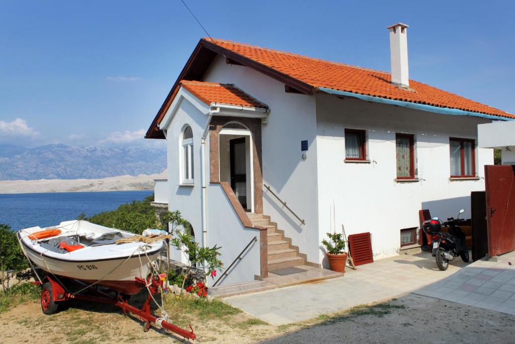 a small white house with a boat in front of it at Apartments with a parking space Bosana, Pag - 9374 in Pag