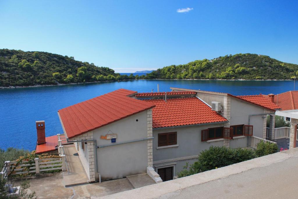 um edifício com telhados vermelhos ao lado de uma massa de água em Apartments by the sea Karbuni, Korcula - 9308 em Prizba