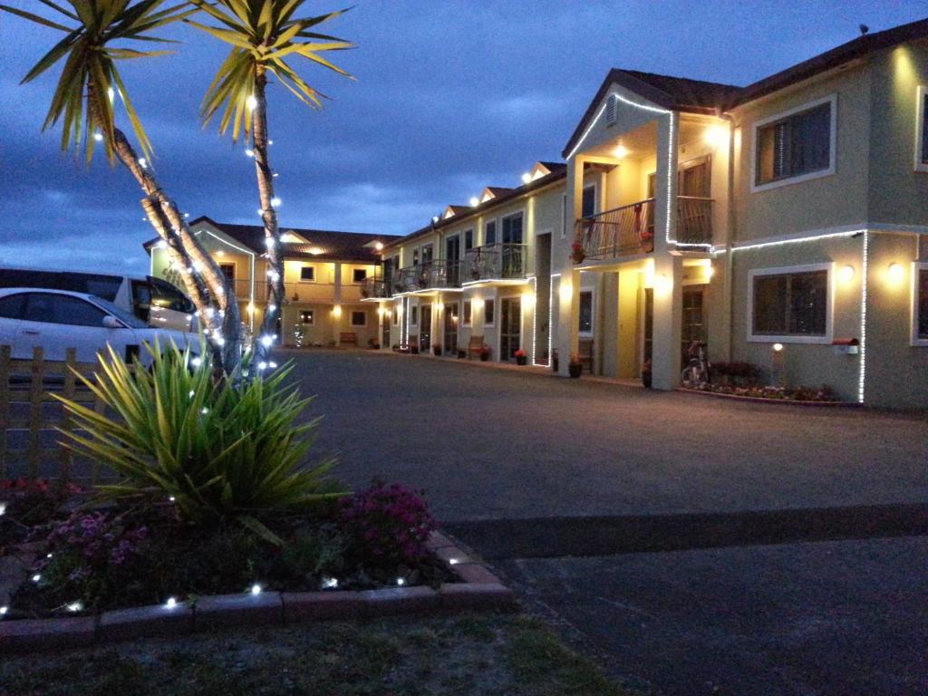 een gebouw met een palmboom en een parkeerplaats bij New Castle Motor Lodge in Rotorua