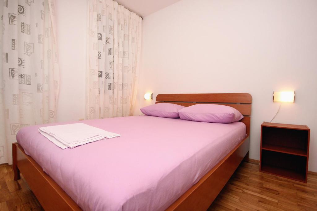 a bed with purple pillows in a small room at Apartments with WiFi Omis - 9460 in Omiš