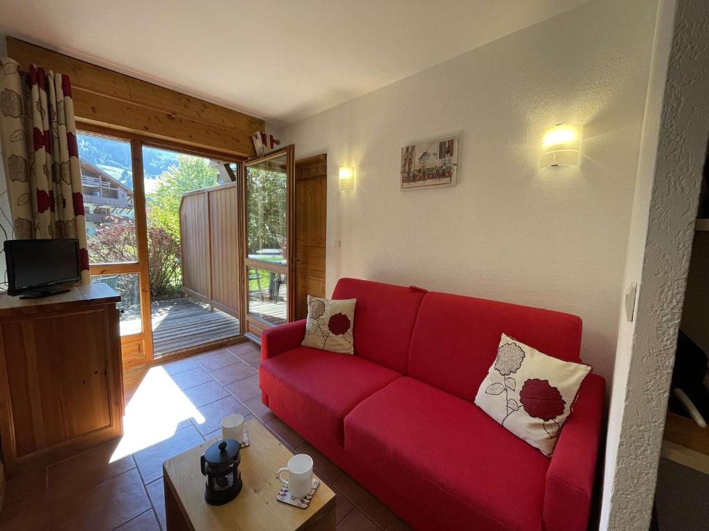een rode bank in een woonkamer met een raam bij Appartement Praz-sur-Arly, 1 pièce, 4 personnes - FR-1-603-63 in Praz-sur-Arly