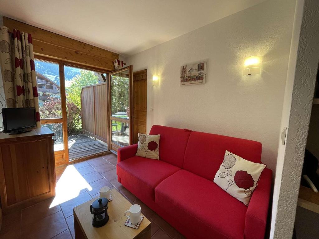 un canapé rouge dans un salon avec une fenêtre dans l'établissement Studio Cabine Praz-sur-Arly - 4 pers, Terrasse, Piscine, Parking, Proche village et pistes - FR-1-603-63, à Praz-sur-Arly