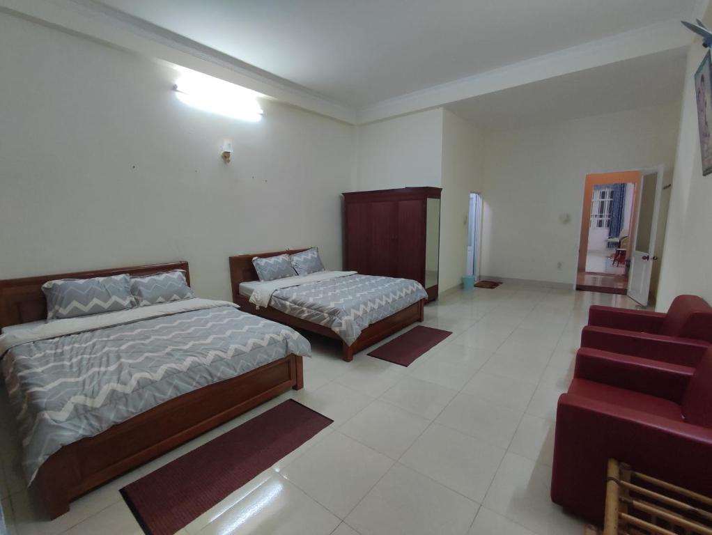 a hotel room with two beds and a chair at Homestay 846/B53 in Vung Tau