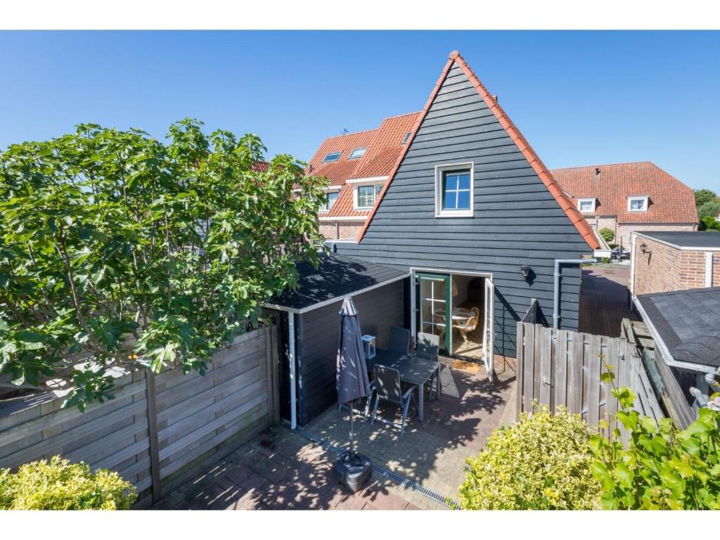 uma casa negra com uma cerca e uma árvore em Quietly located house within walking distance of the beach em Domburg