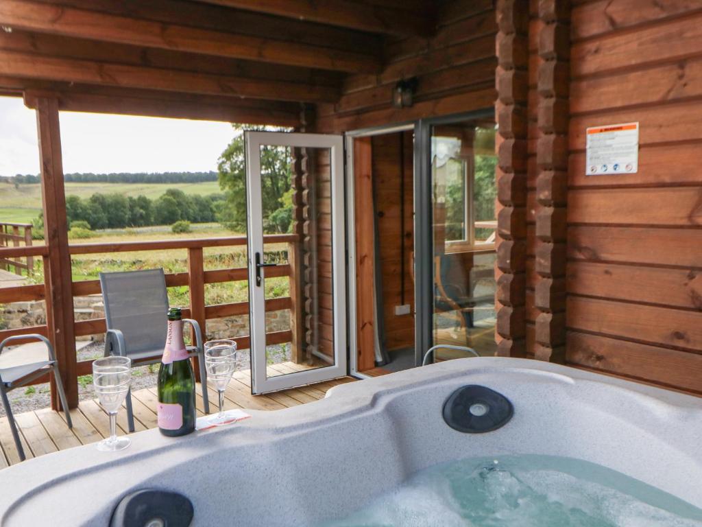 a bath tub with a bottle of wine in a cabin at Pheasant in Barnard Castle