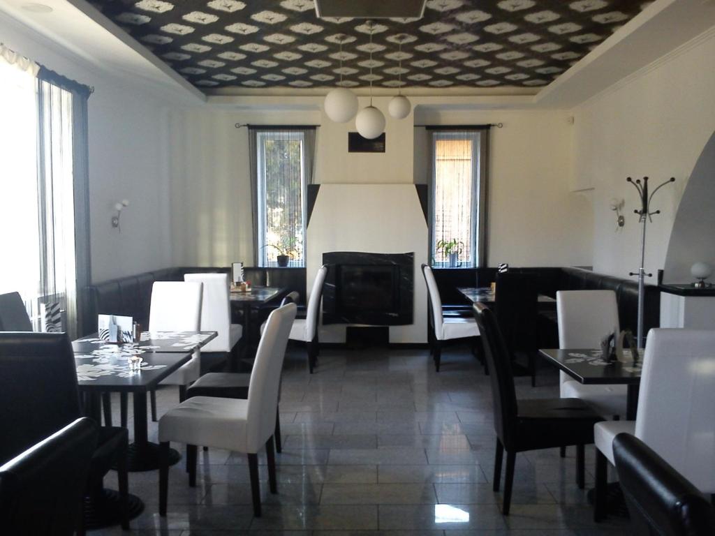 una sala da pranzo con tavoli, sedie e finestre di OP-ART Étterem és Panzió a Monor