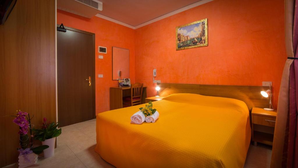 a bedroom with a yellow bed and orange walls at Hotel Venezia in Caorle