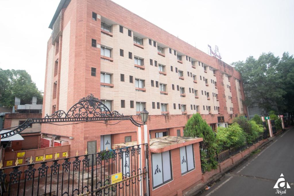 a large brick building with a gate in front of it at Hotel Abigail Goradia's in Shirdi