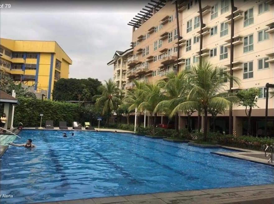 a large swimming pool with palm trees and buildings at The Rochester Parklane Condominium in Manila