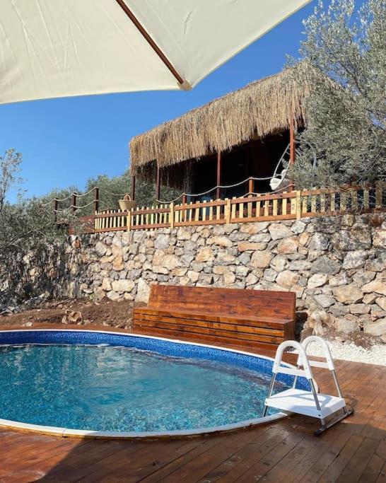 a swimming pool with a bench and a stone wall at Lovin Gocek & Tiny house Mermaid in Fethiye